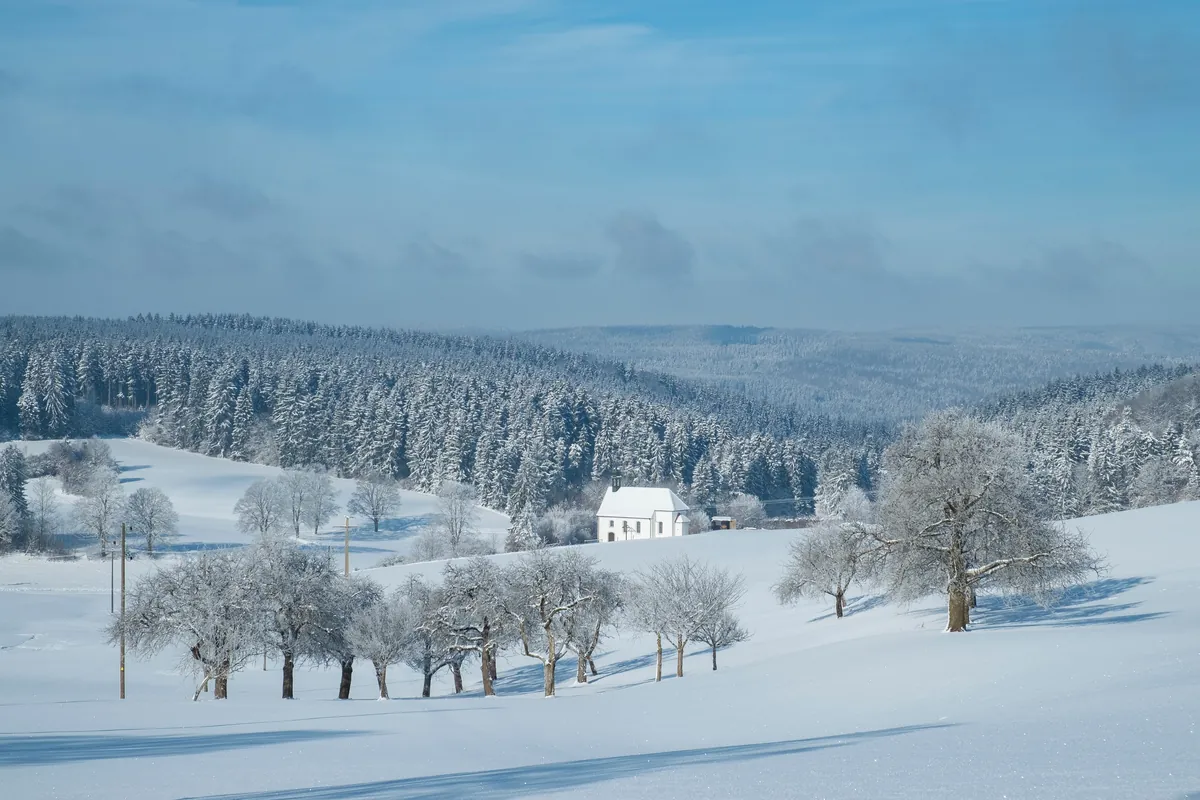 Snow-covered winter landscape with a chapel and orchard meadow near Tuttlingen