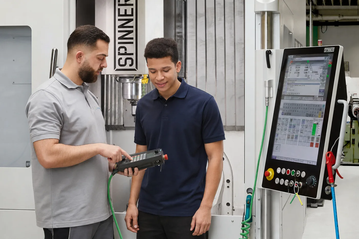 Ausbilder zeigt einem Auszubildenden die Bedienung einer CNC-Maschine